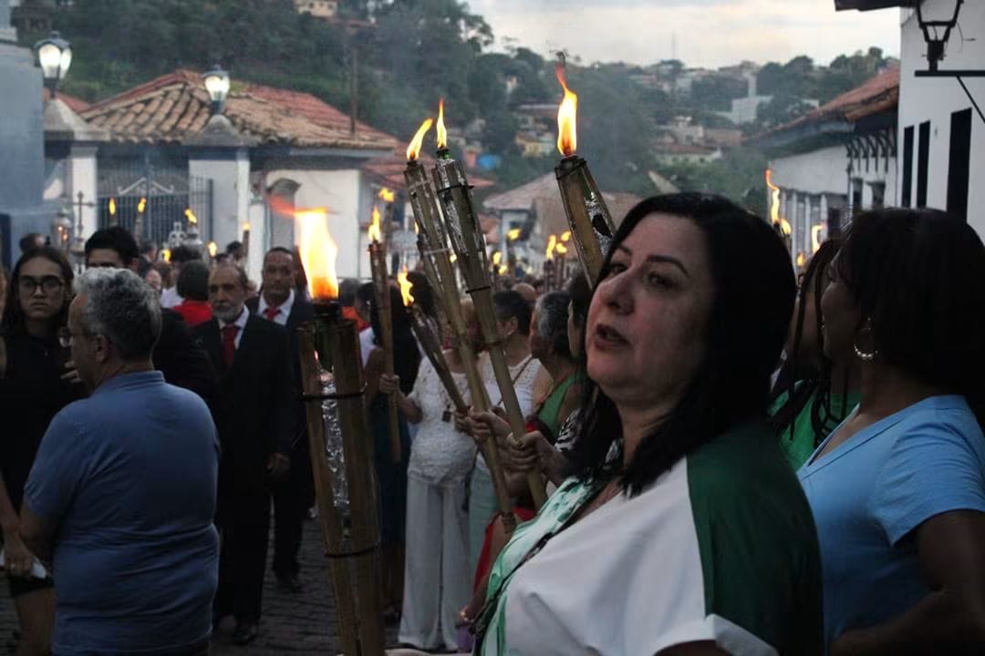 Fiéis caminham juntos levando tochas durante a procissão
